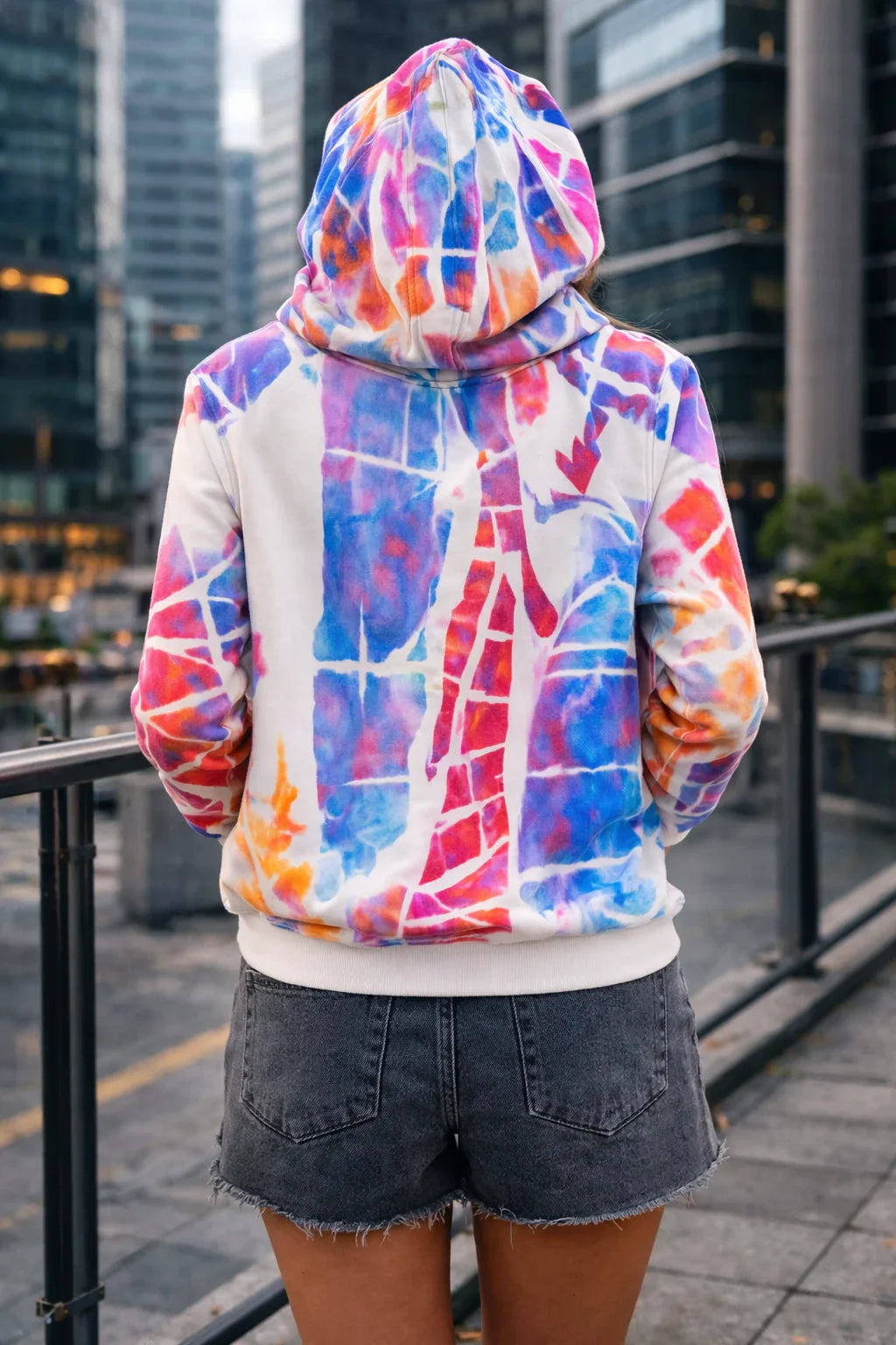 Sudadera con capucha pintada a mano, diseño maximalista multicolor, mujer de espaldas.
