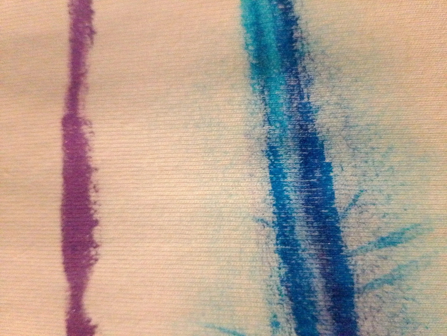Détail d'un tissu peint à la main avec des lignes bleues et violettes sur fond blanc